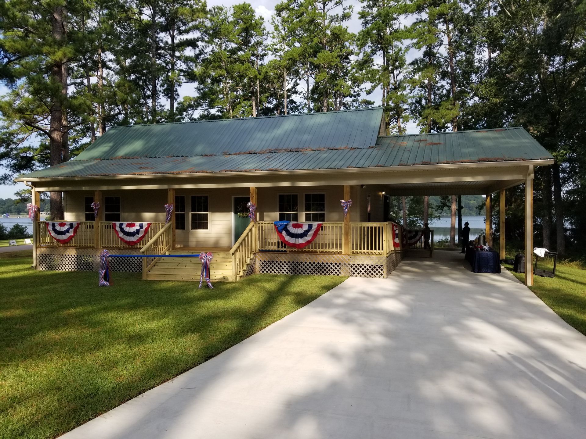 Cottage with porch, driveway, and carport decorated with red, white, and blue bunting.