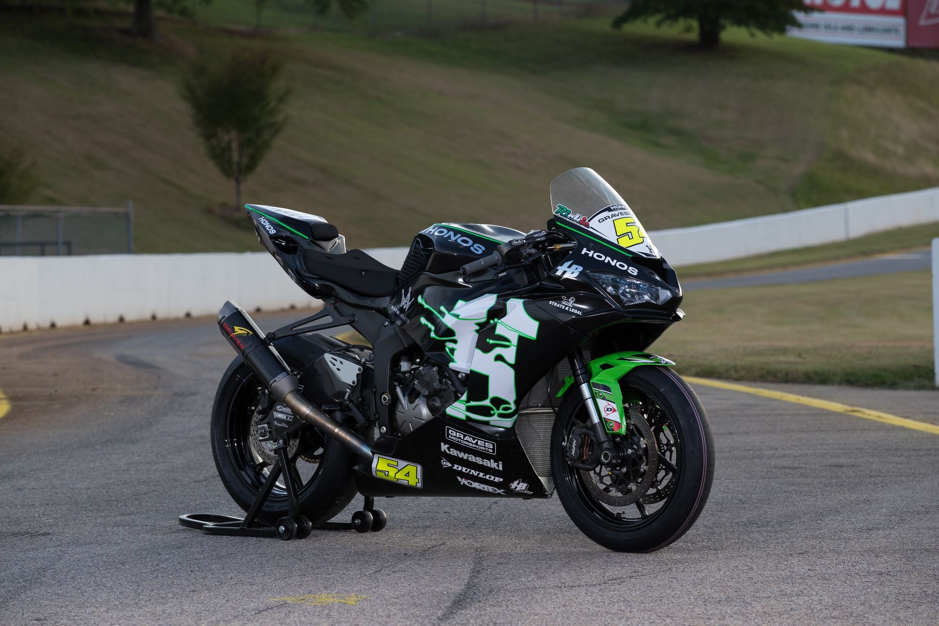 Green and black Kawasaki Ninja ZX-6R sportbike on a racetrack, angled right.