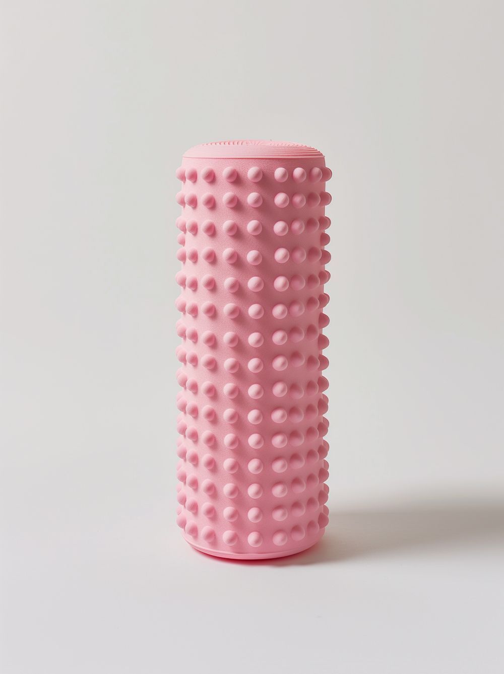 Green, textured foam roller with small bumps, used for muscle therapy.