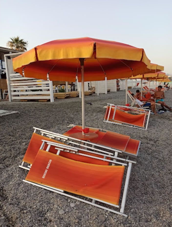 Una fila di sedie arancioni e ombrelloni su una spiaggia