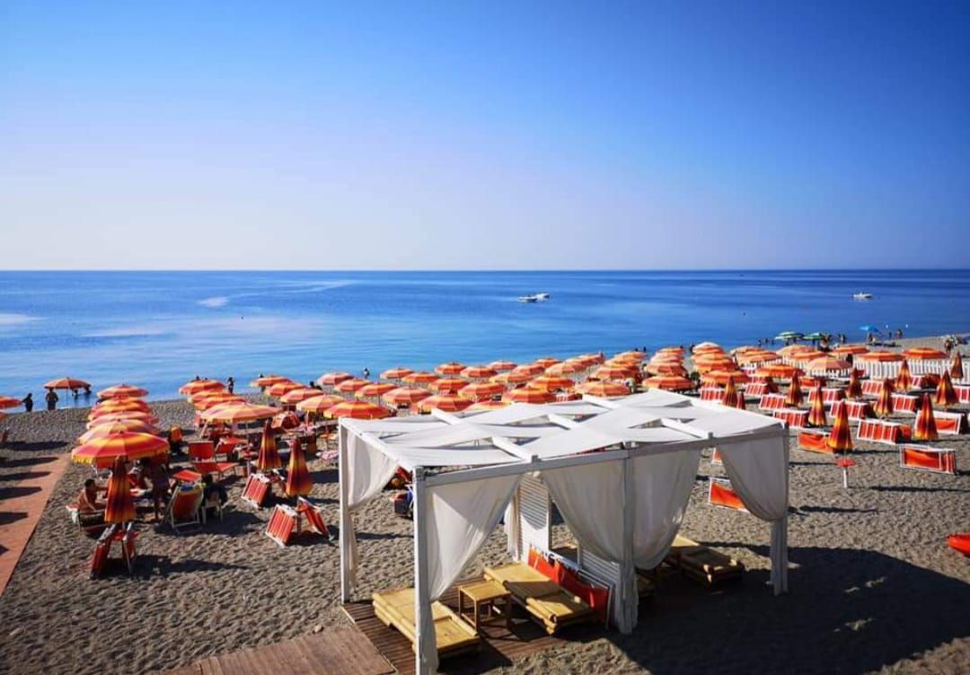 Una spiaggia con tanti ombrelloni e una tettoia bianca che si affaccia sull'oceano.