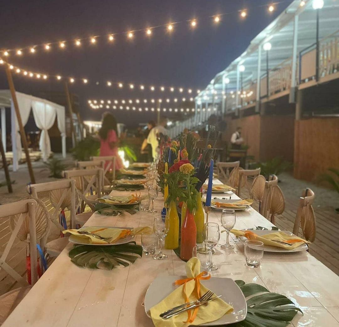 Un lungo tavolo con piatti, bicchieri e fiori.