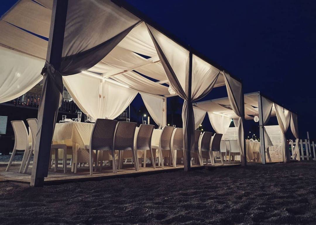 Una fila di tavoli e sedie sotto una tenda di notte