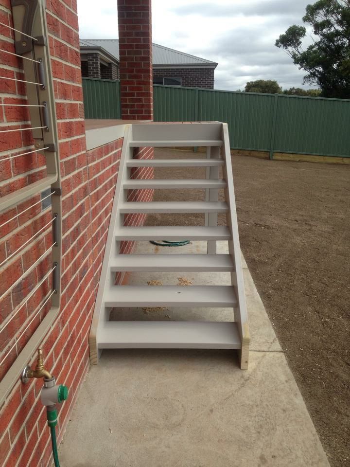 Outdoor stairs painted light gray next to a brick building.