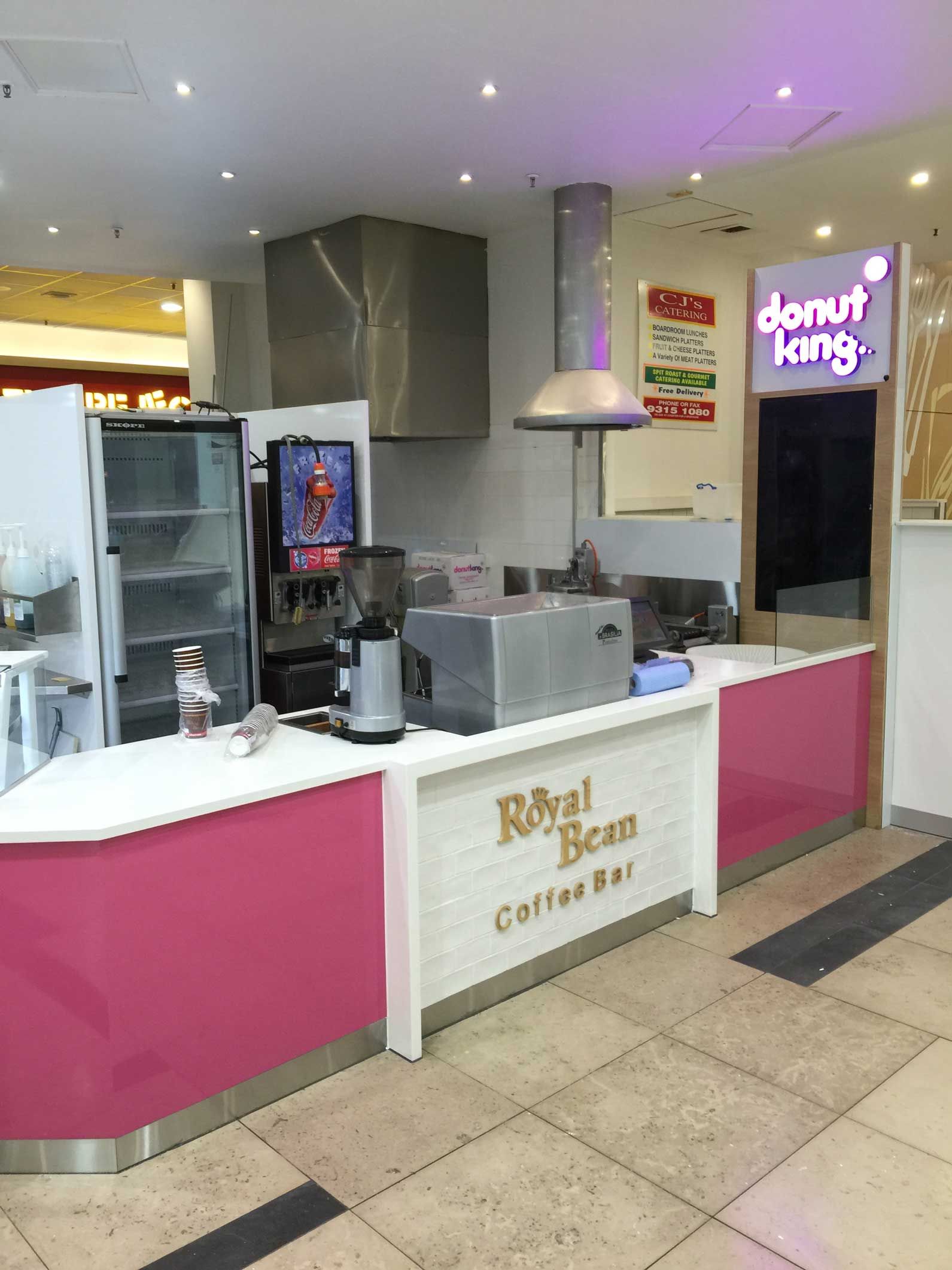Royal Bean Coffee Bar with pink and white counter in a mall setting.