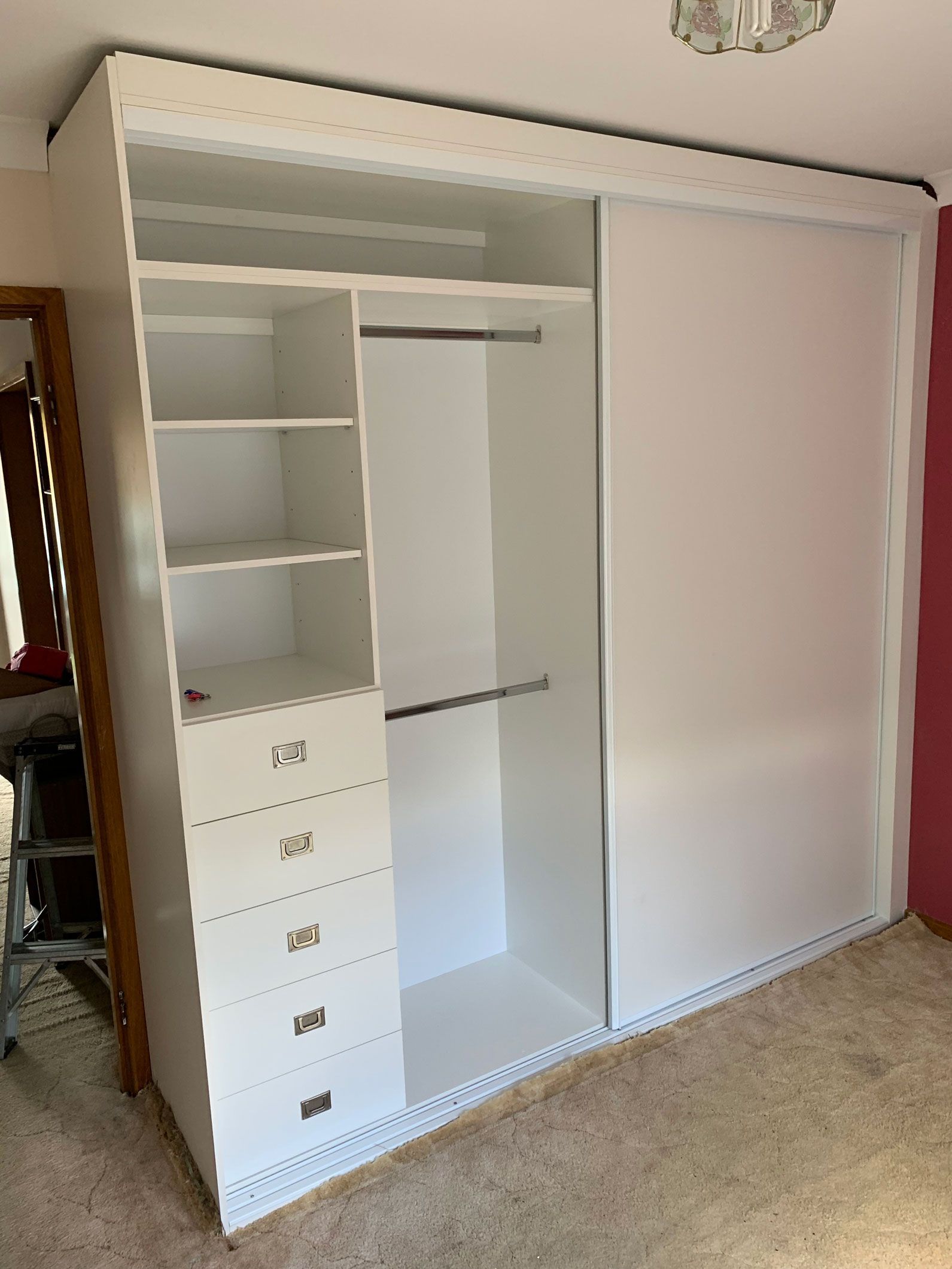 White sliding-door wardrobe with shelves, drawers, and hanging rod. Interior is white.