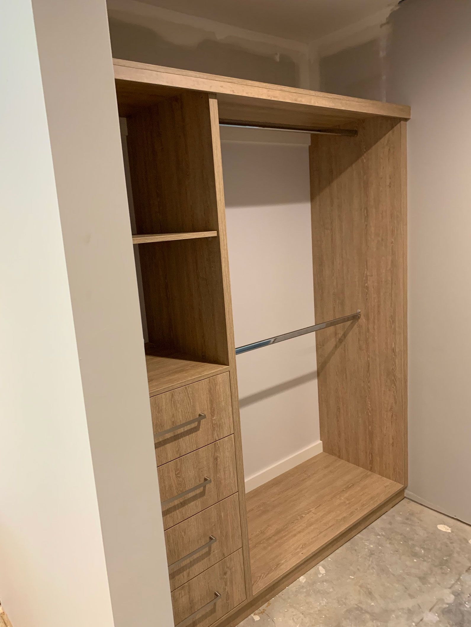 Built-in closet with shelves, drawers, and hanging rods. Light wood finish.