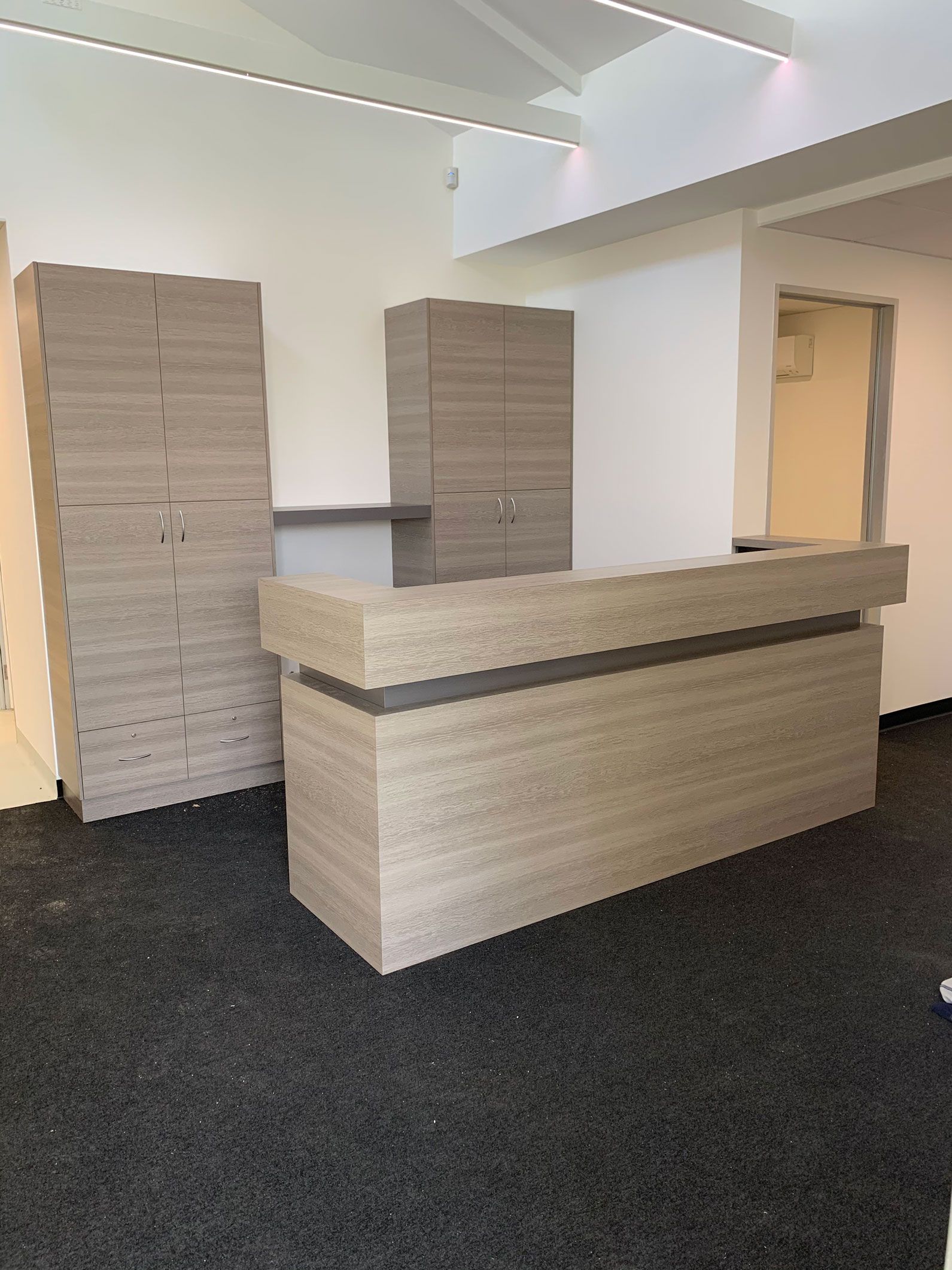 A new office reception desk and storage cabinets assembled from particle board on a dark floor, waiting to be installed.