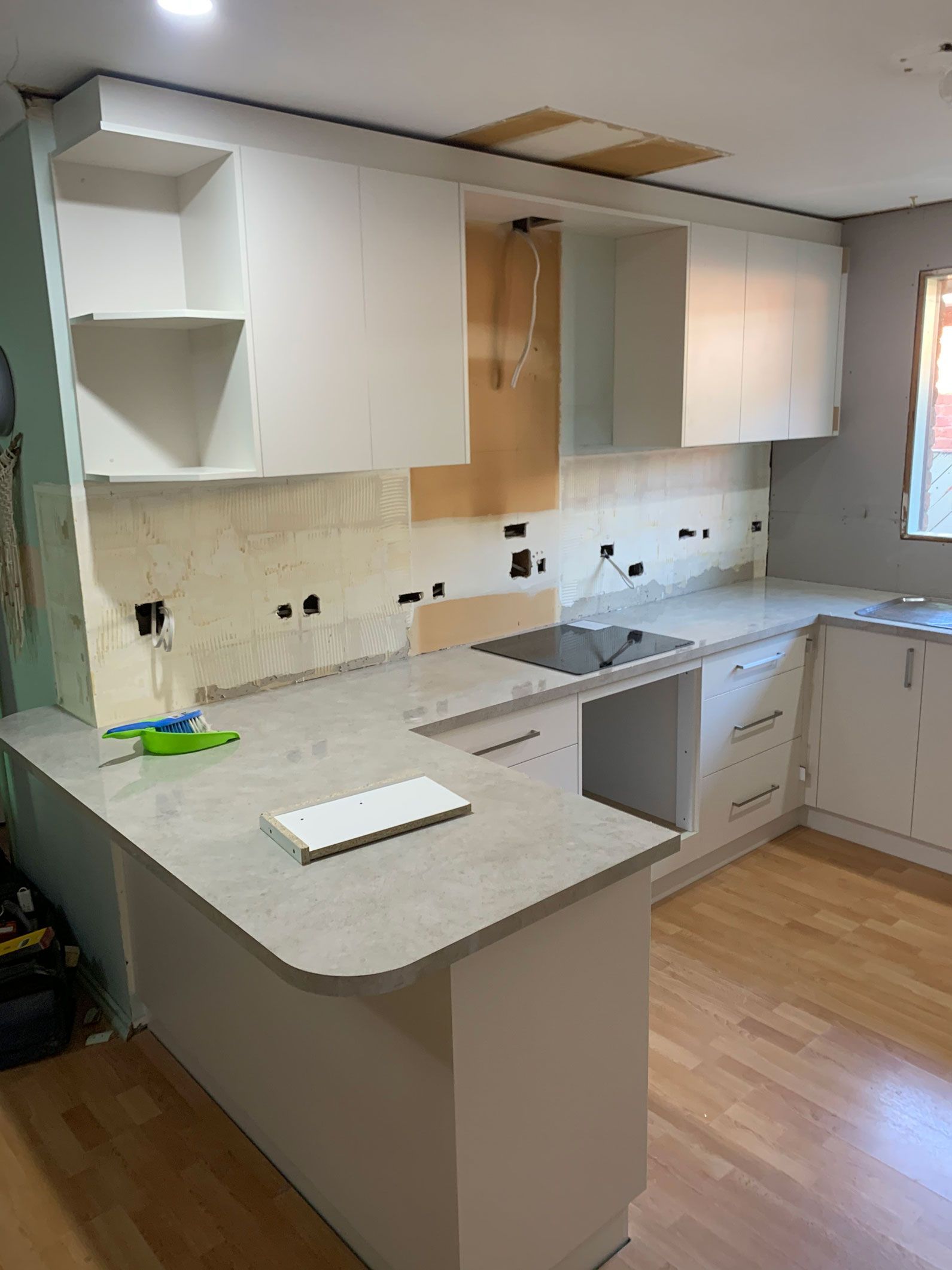 Kitchen with unfinished white cabinets, light countertop, and light wood flooring.