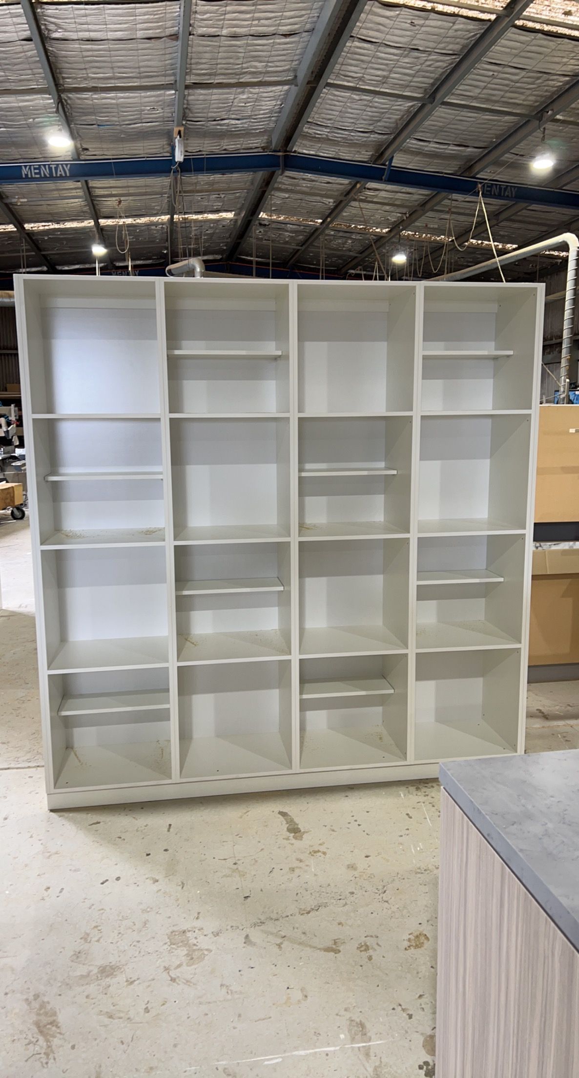 White, multi-compartment shelving unit in a warehouse.