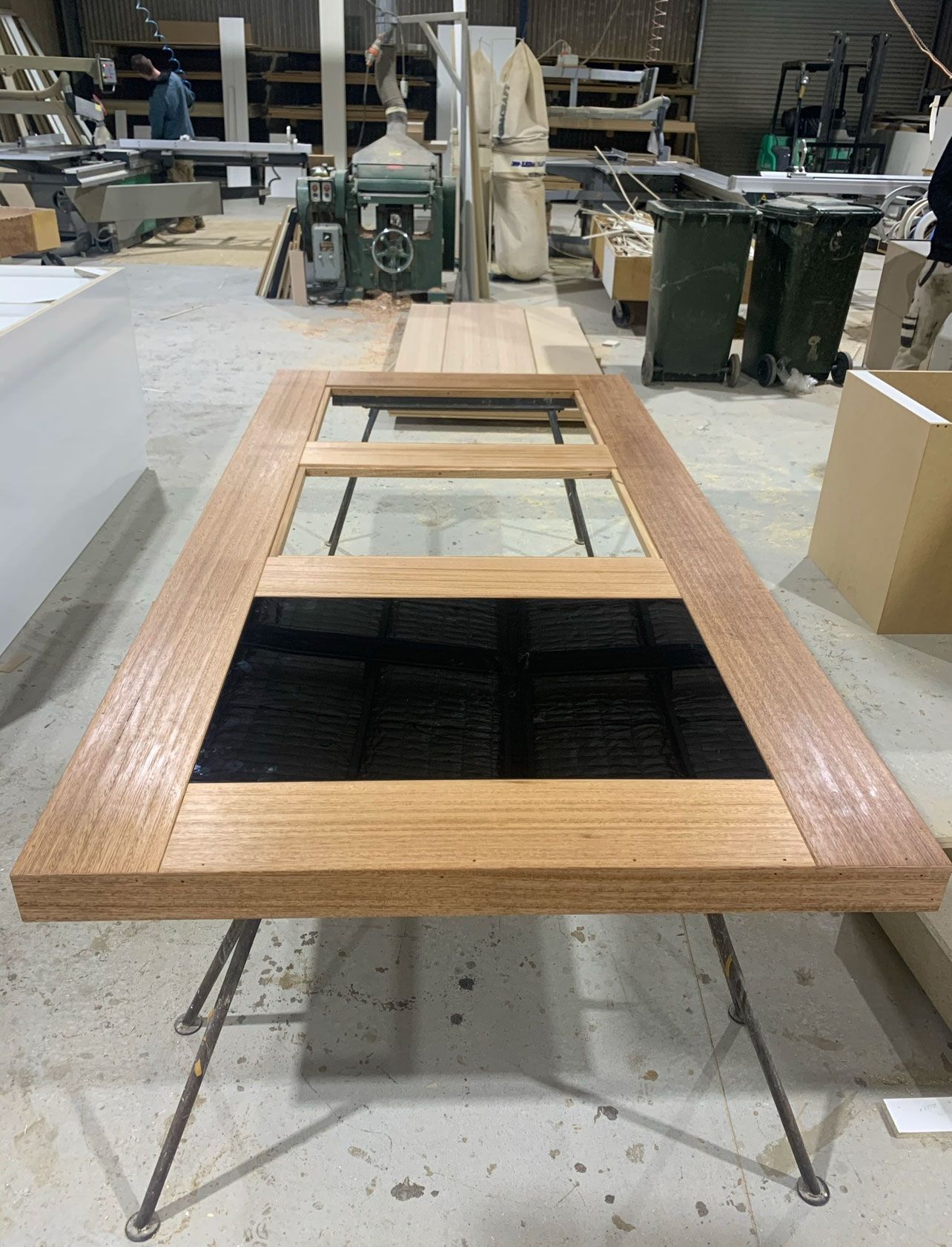 A wooden door with glass panels on sawhorses in a workshop.