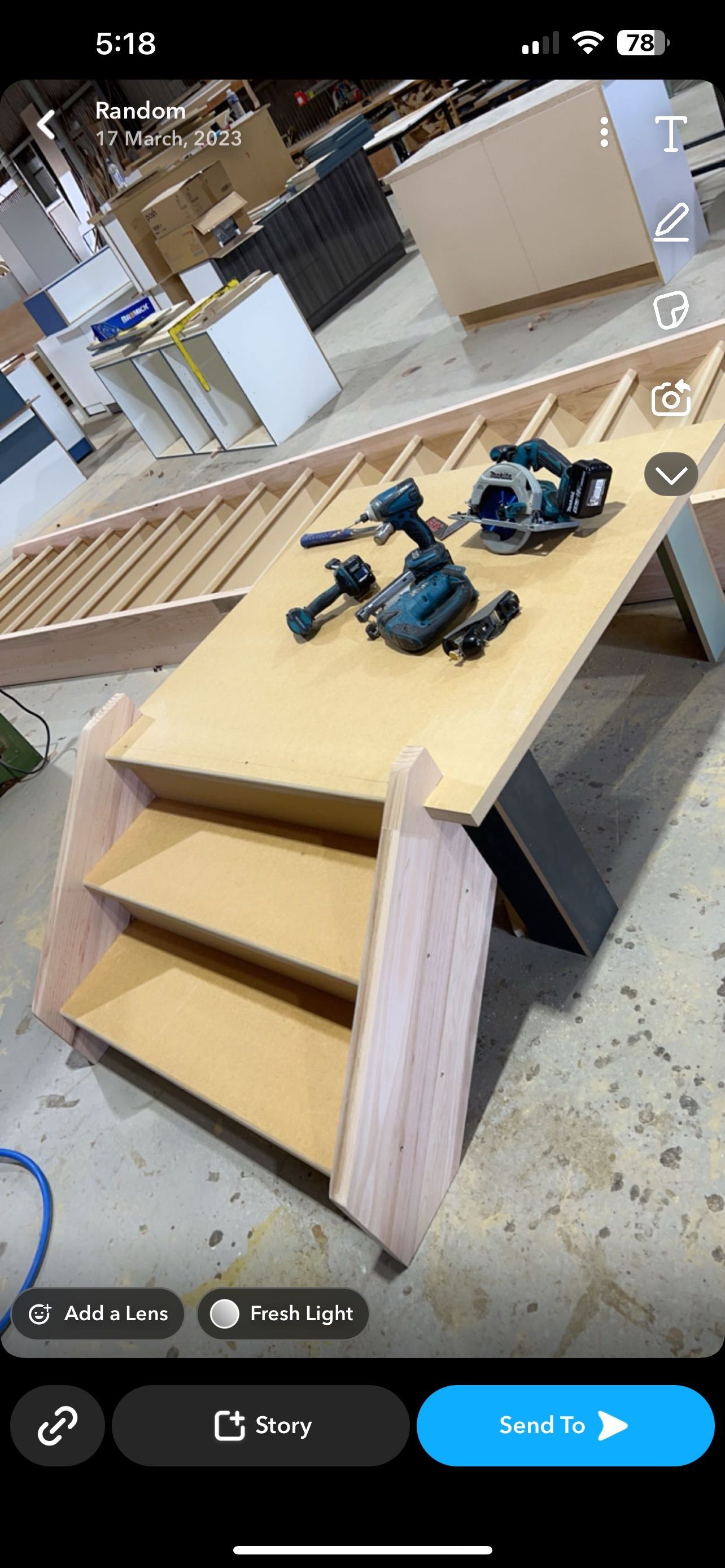 A wooden staircase with power tools on a plywood platform in a workshop.