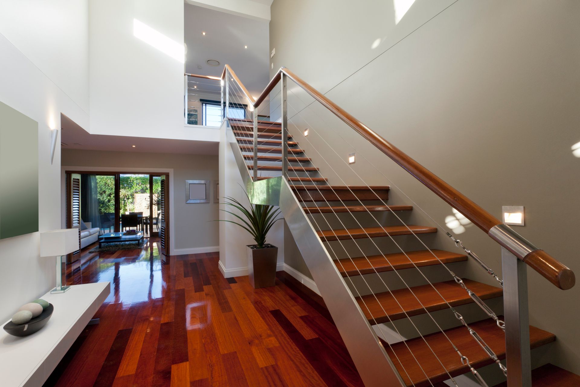 Modern interior with wooden staircase, steel cables, and hardwood floors.
