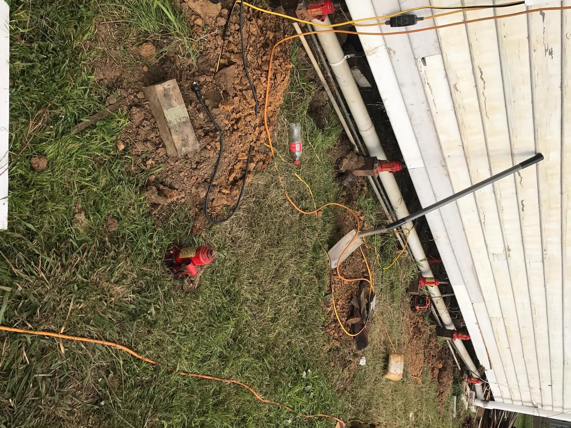 A person is digging a hole in the ground next to a house.