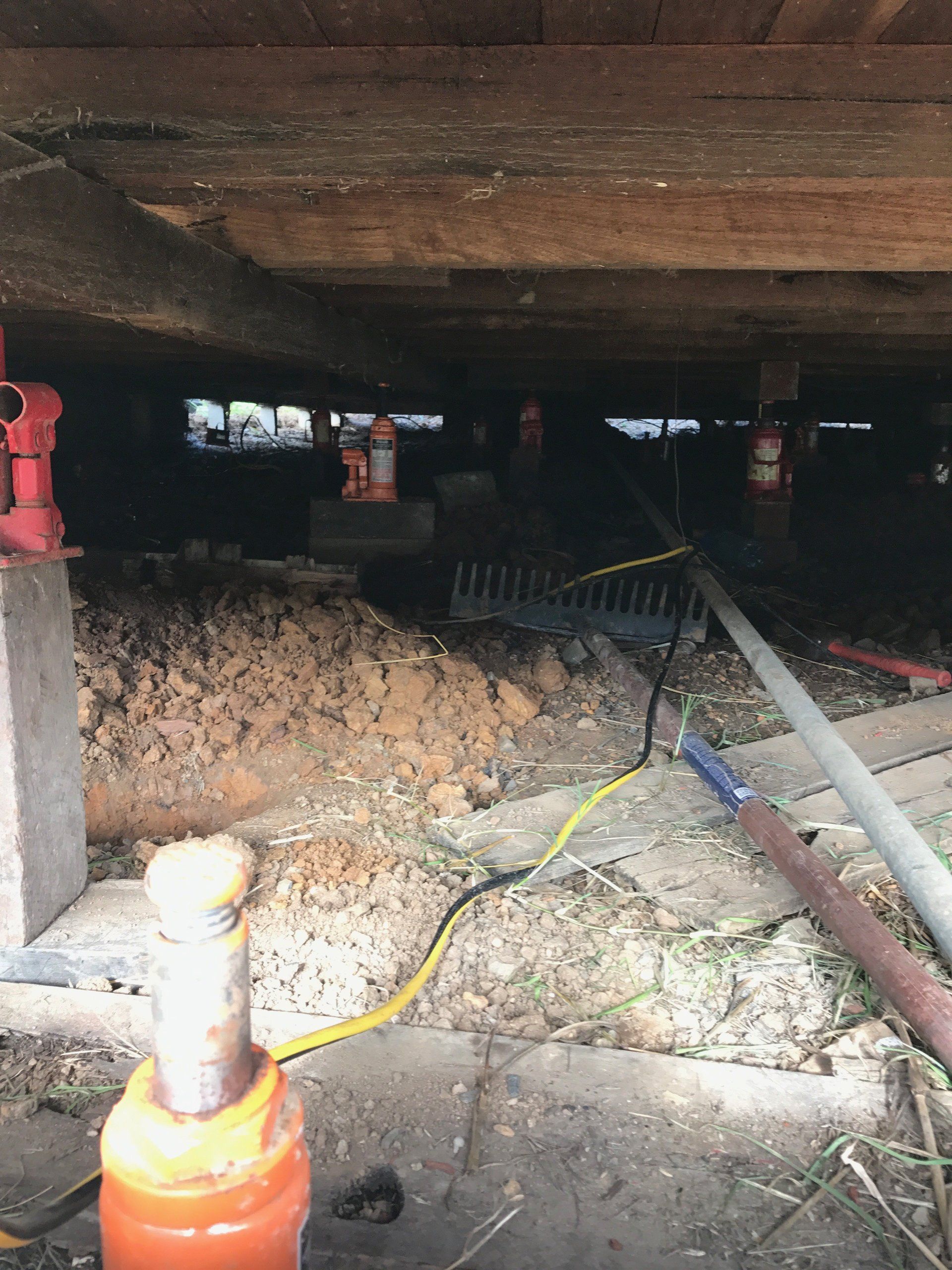 A hydraulic jack is sitting under a house.