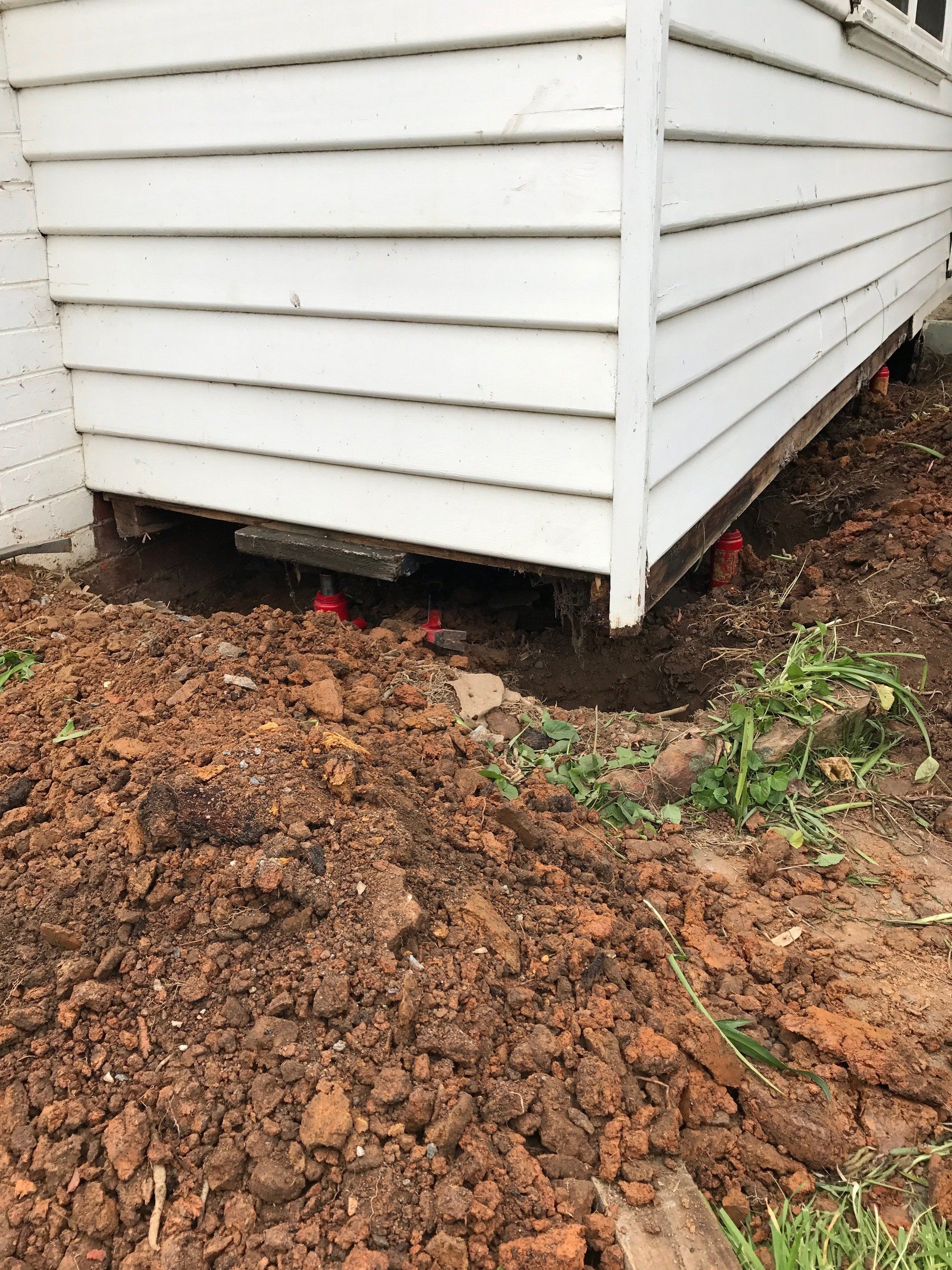 A white house is sitting in the dirt next to a pile of dirt.