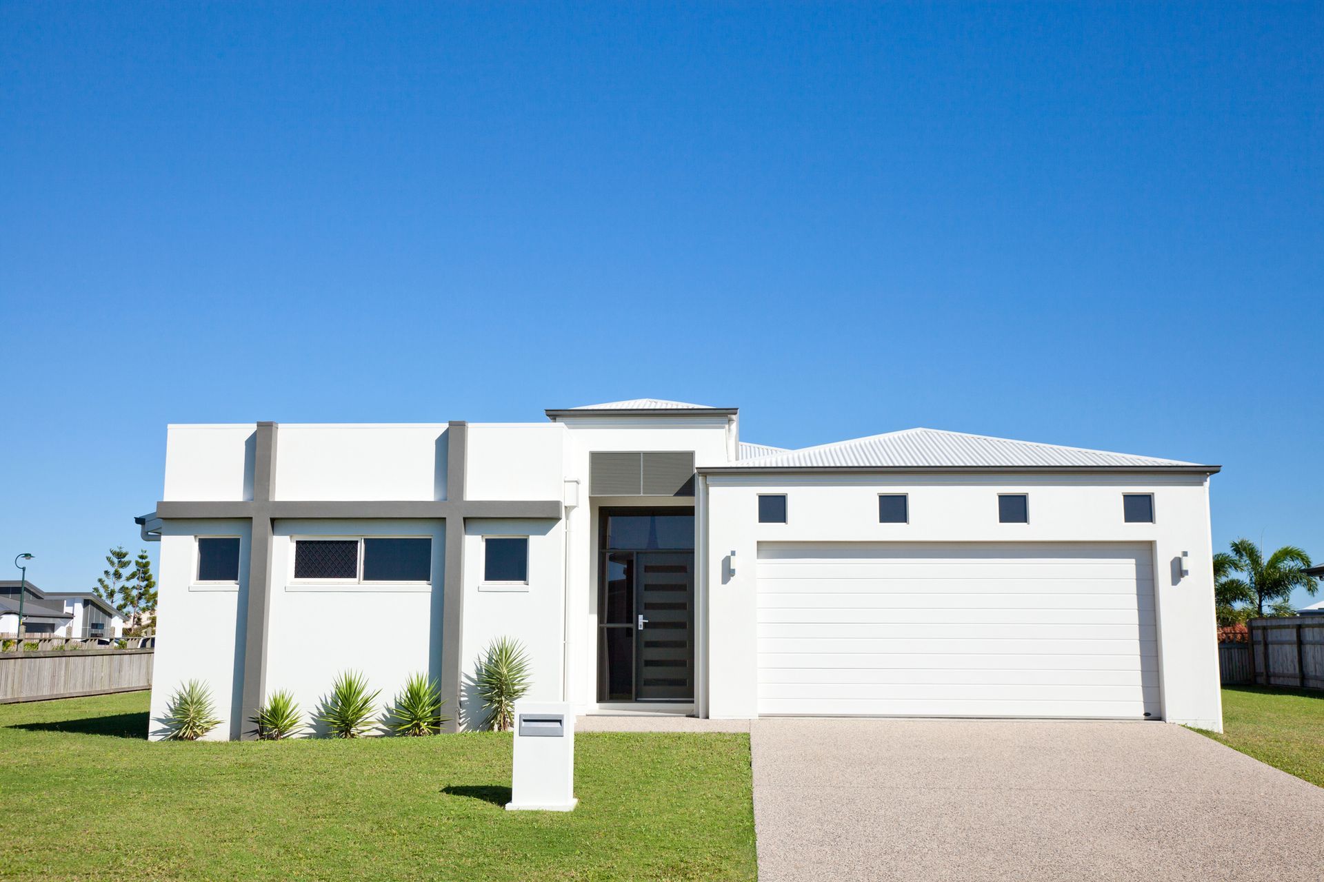A white house with a white garage door and a blue sky in the background