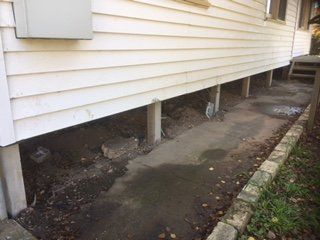 A white house with a concrete sidewalk in front of it.