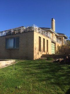 A large brick house with a balcony and a chimney on top of it.
