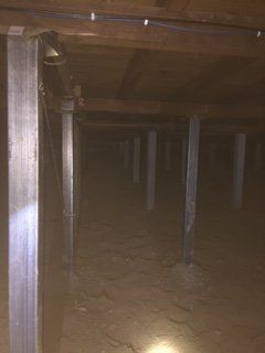 A dark room with a lot of pillars and a light on the ceiling.