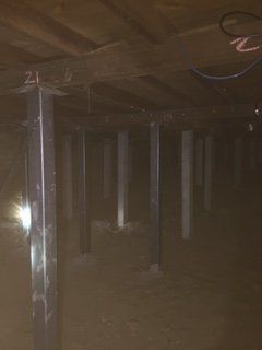 A dark basement with a light shining through the ceiling.