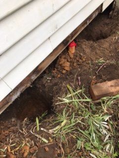 A white house with a hole in the ground underneath it.