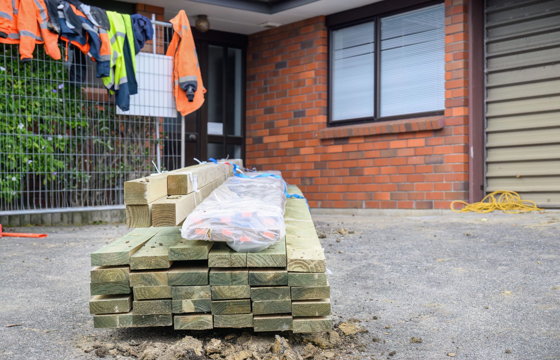 Treated retaining timbers piled on the driveway for a house restumping service.