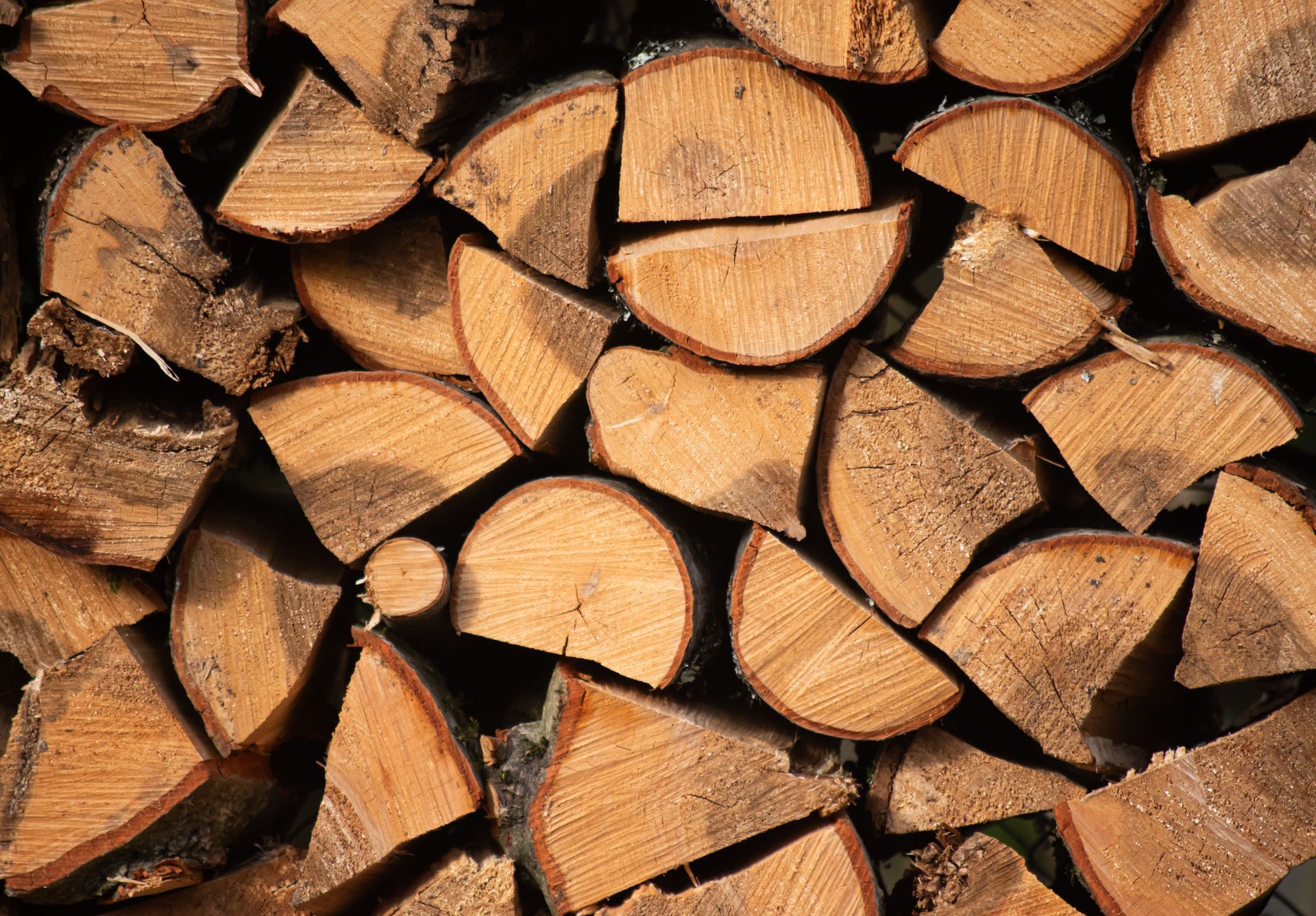 Stacked brown wooden logs in a neat pile.