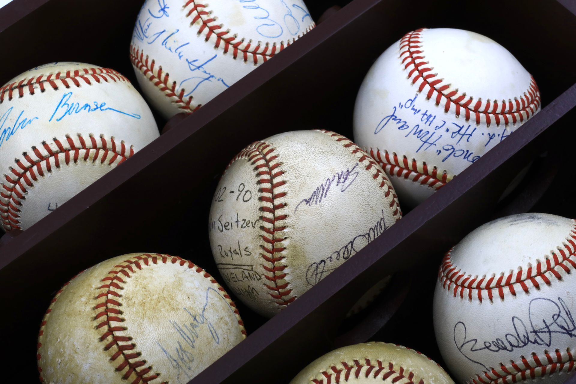 Black baseball display with three rows of signed balls.