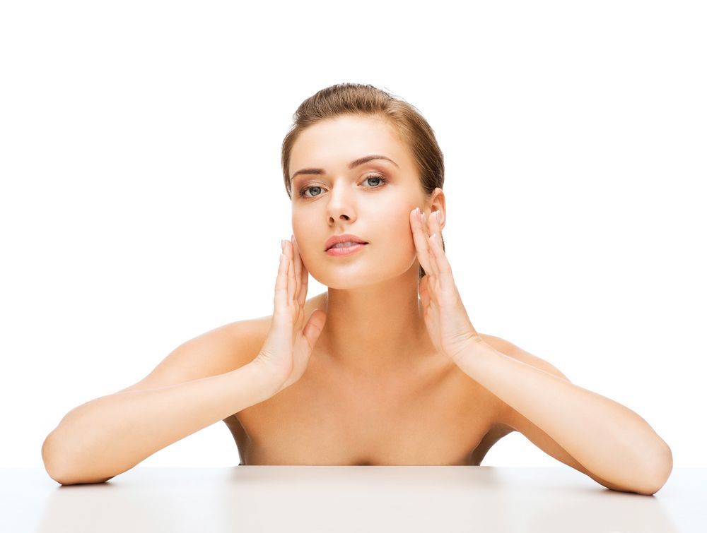 A woman is sitting at a table with her hands on her face.