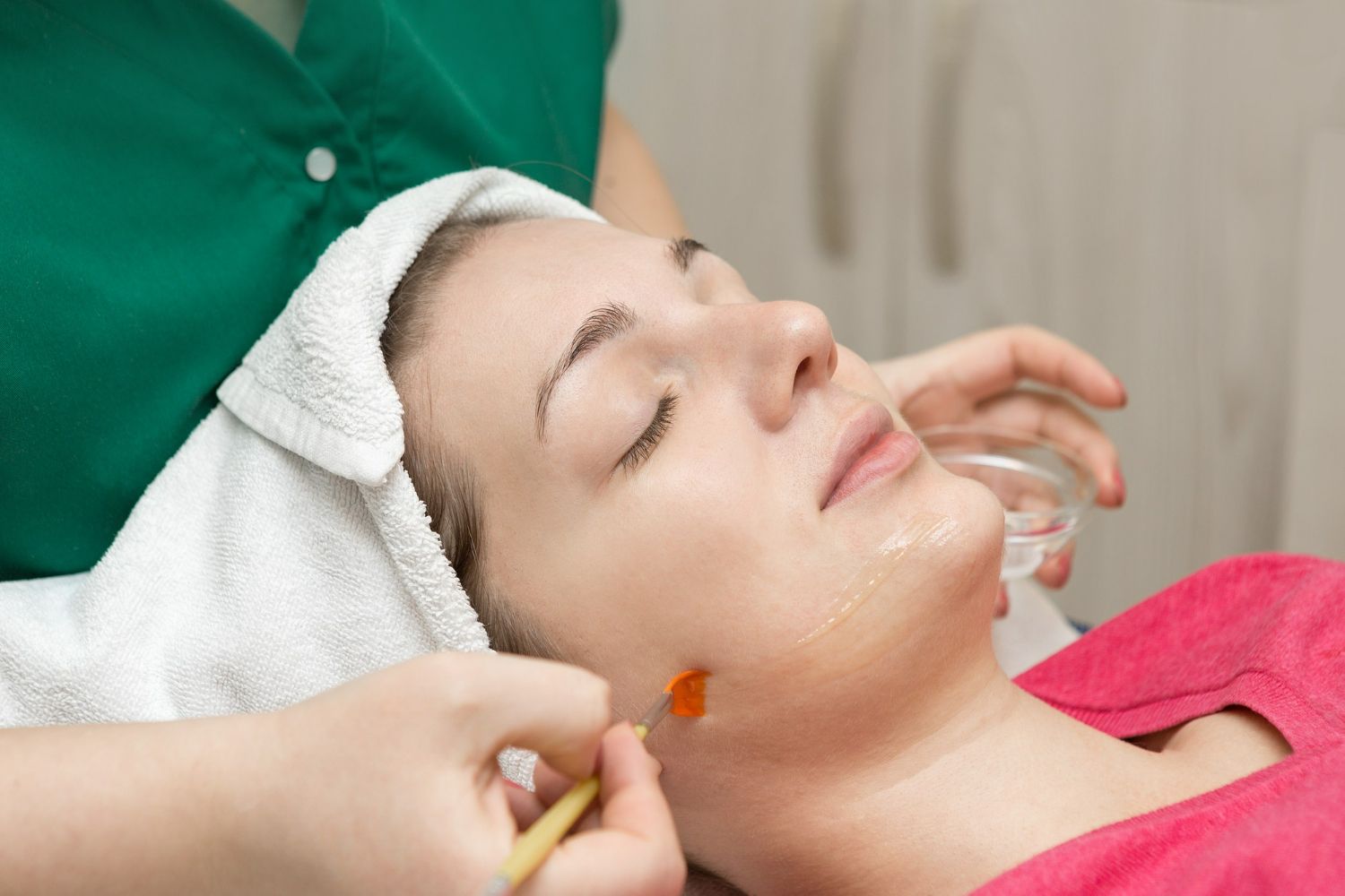 Woman receiving a facial treatment with eyes closed, in a spa setting.