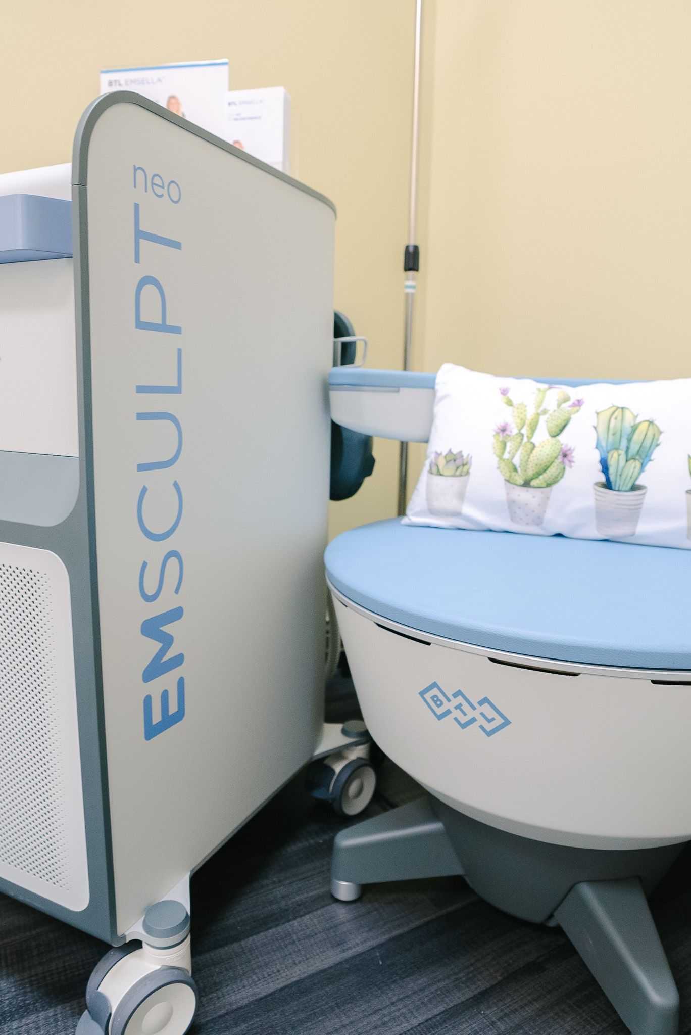 EmSculpt machine beside a padded treatment chair in a clinic room