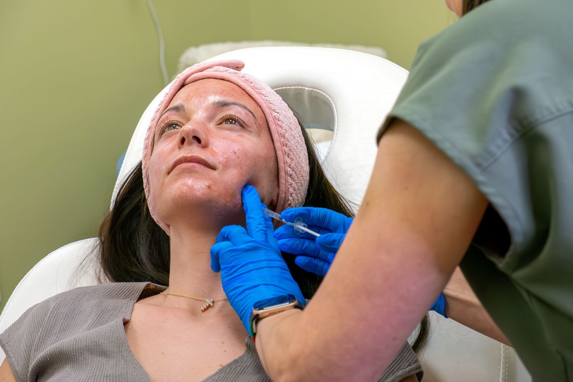 Patient reclining in a dental chair while a gloved clinician examines her mouth