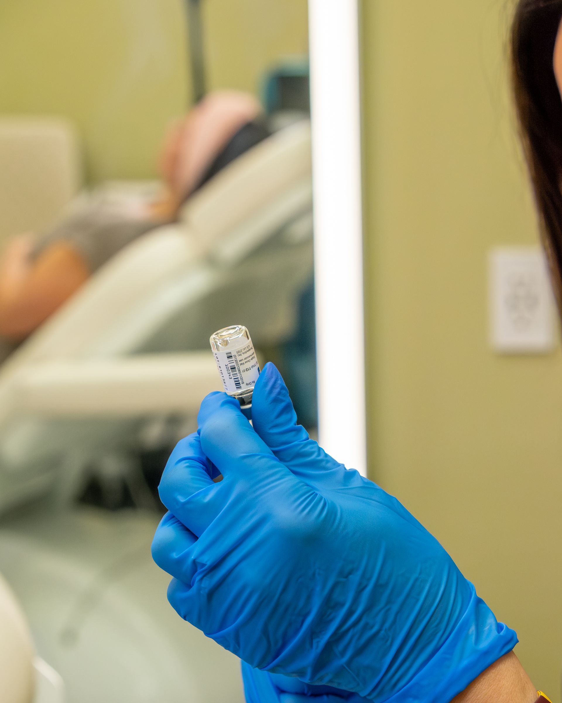 Gloved hand holding a small test tube in a clinical setting