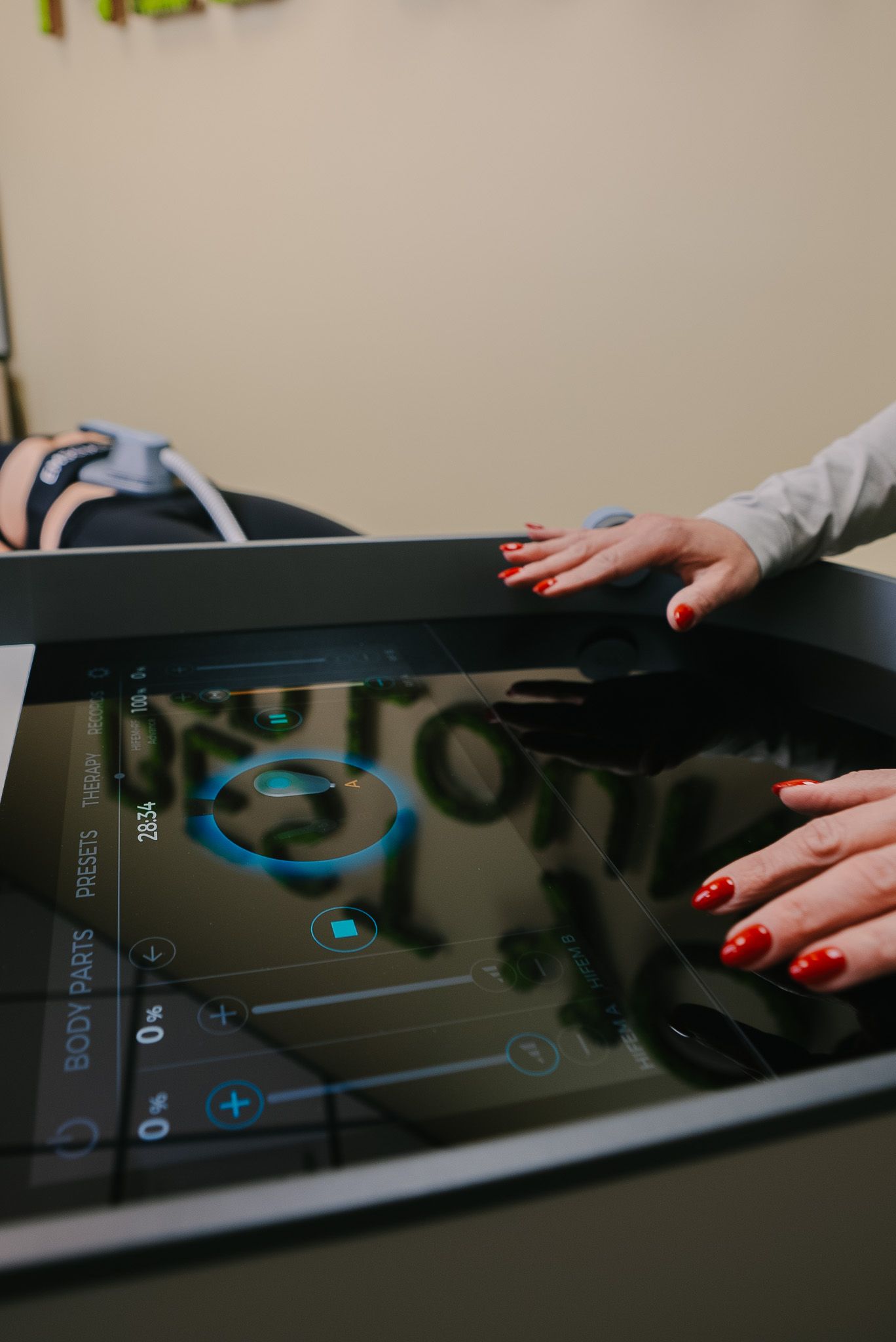 A woman with red nails is touching a screen on a table.
