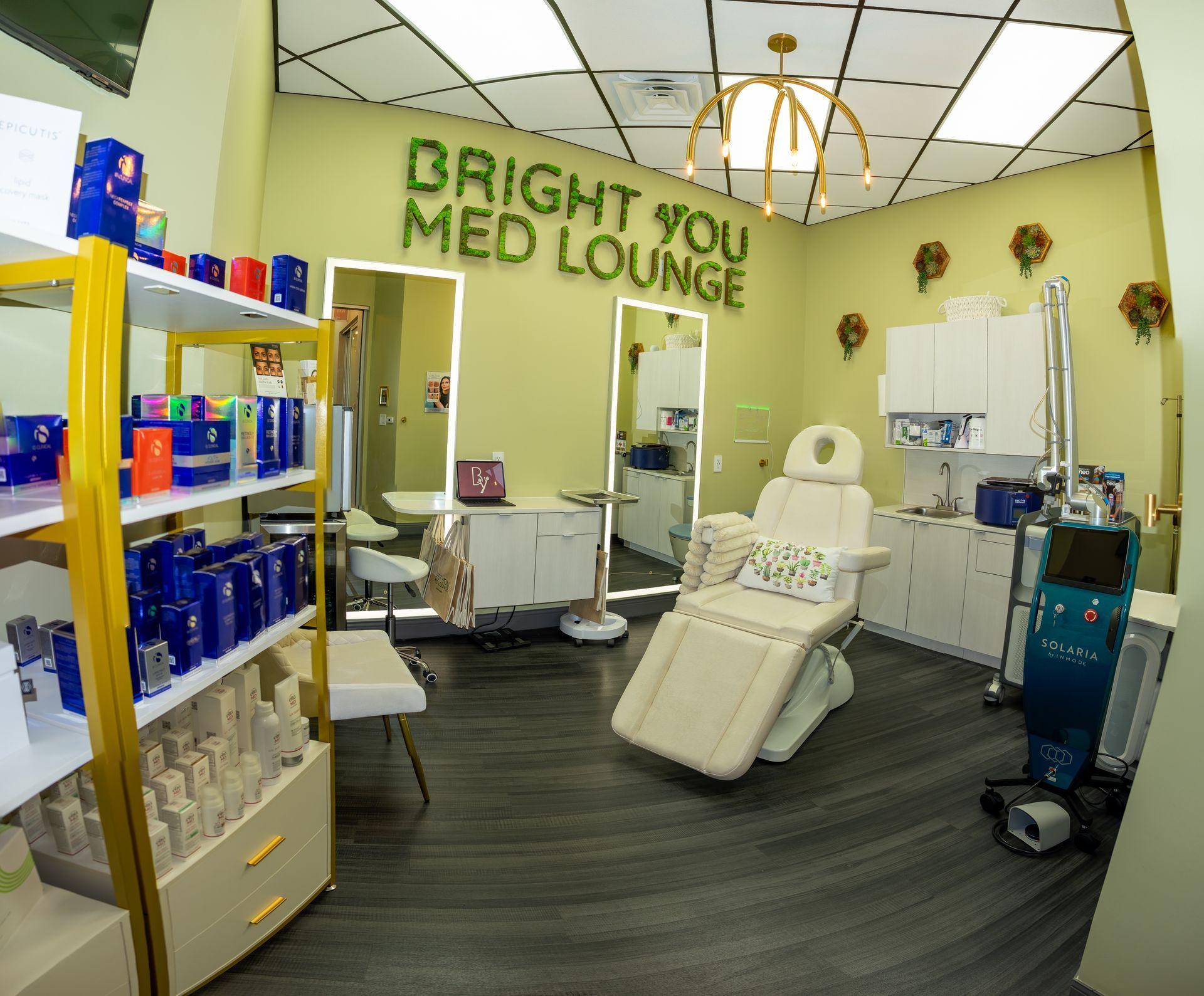 Bright You Med Lounge interior. Medical chair, products on shelves, mirrors, and modern lighting. Green and white decor.