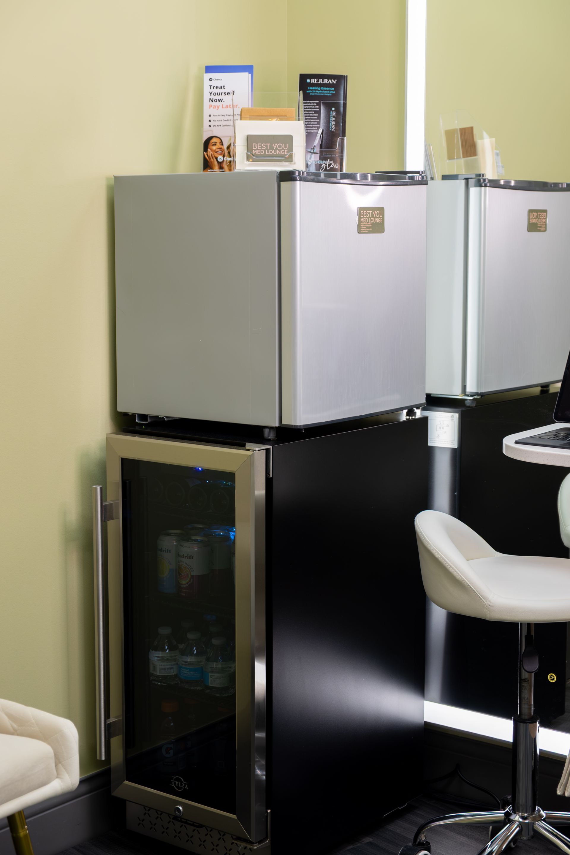 A small refrigerator is sitting on top of a smaller refrigerator in a room.