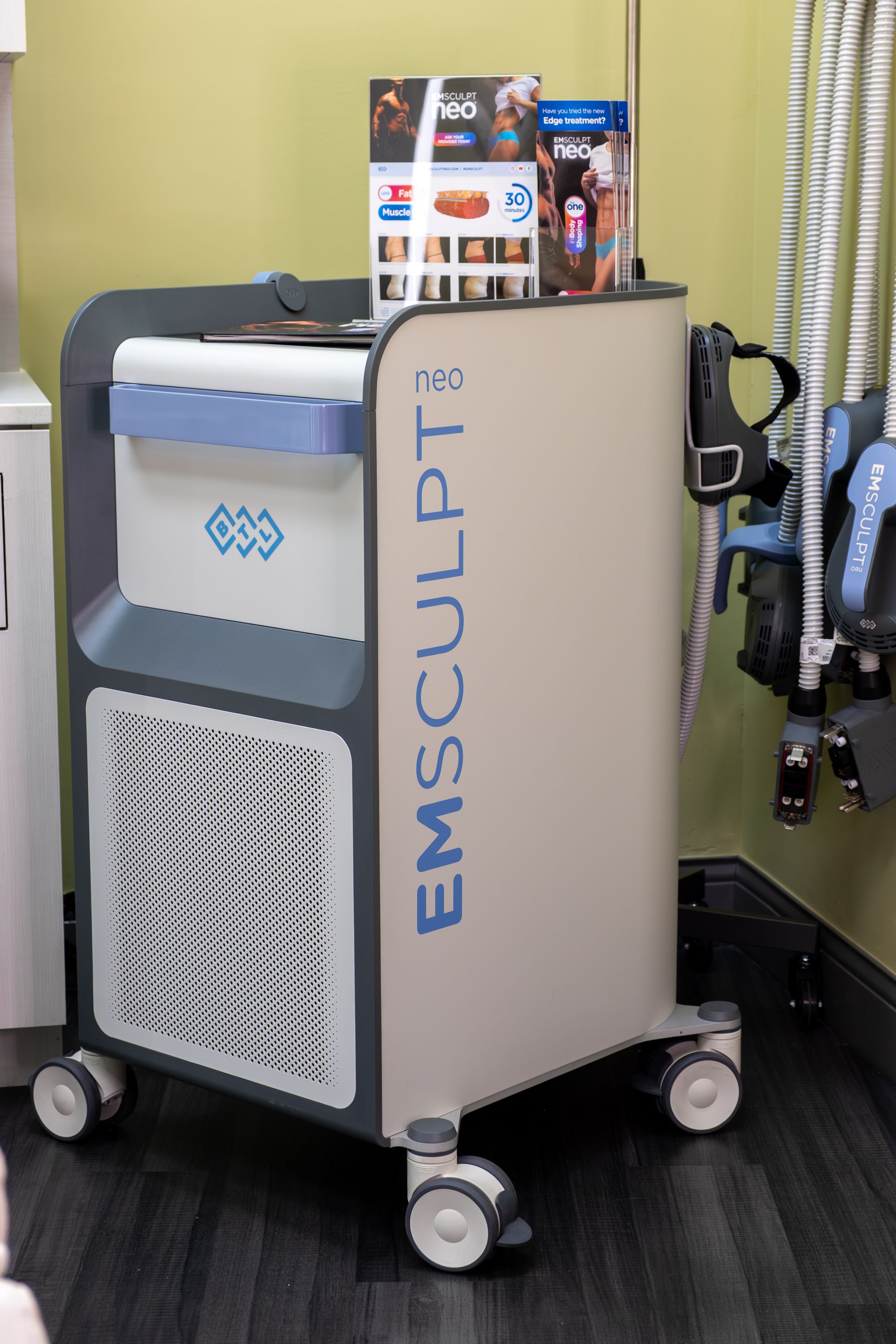 A machine called emsculpt is sitting on a cart in a room.