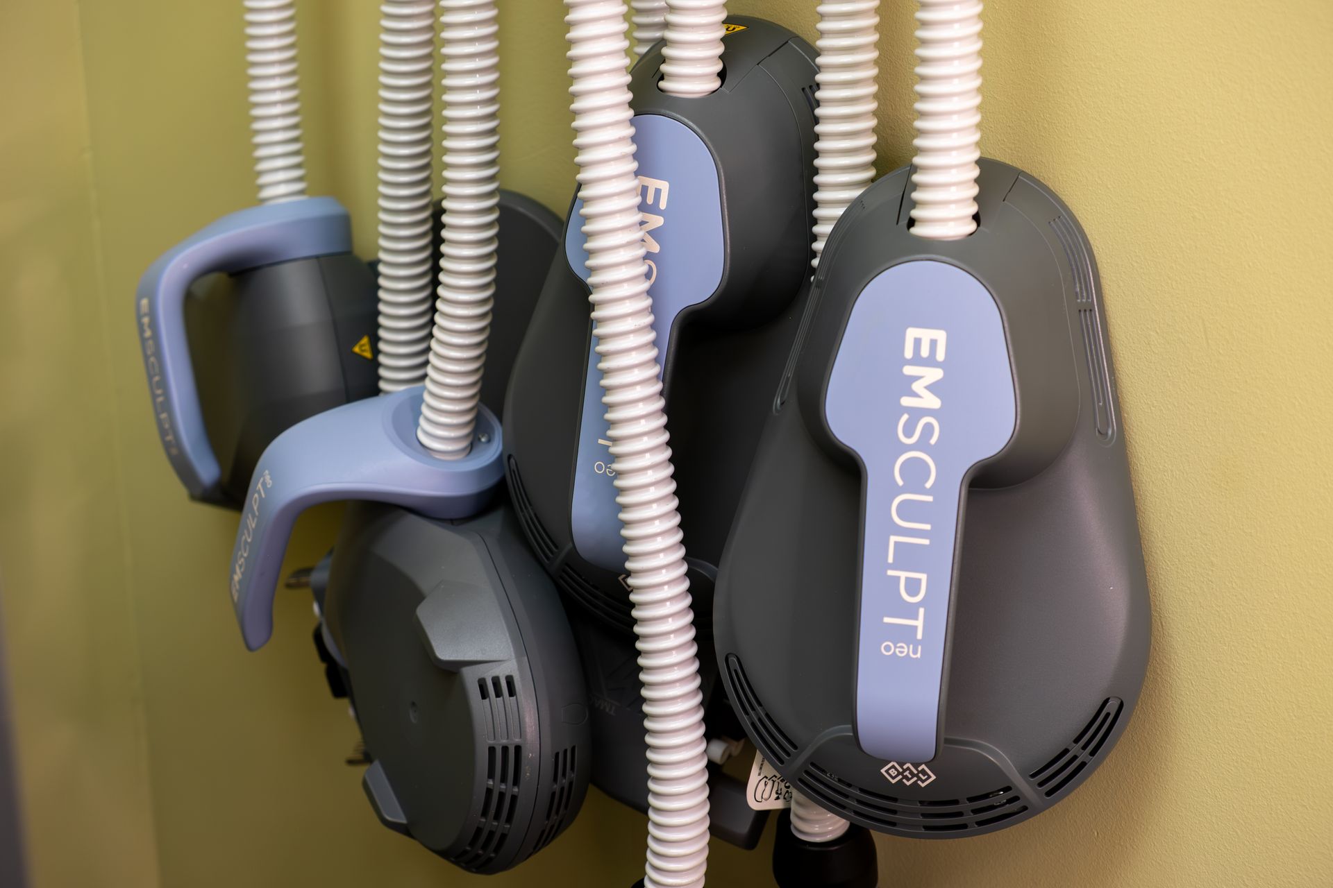 A bunch of emsculpt machines are hanging on a wall.