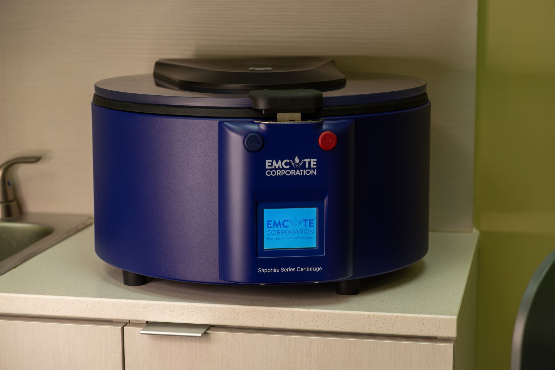 A blue centrifuge is sitting on top of a counter next to a sink.