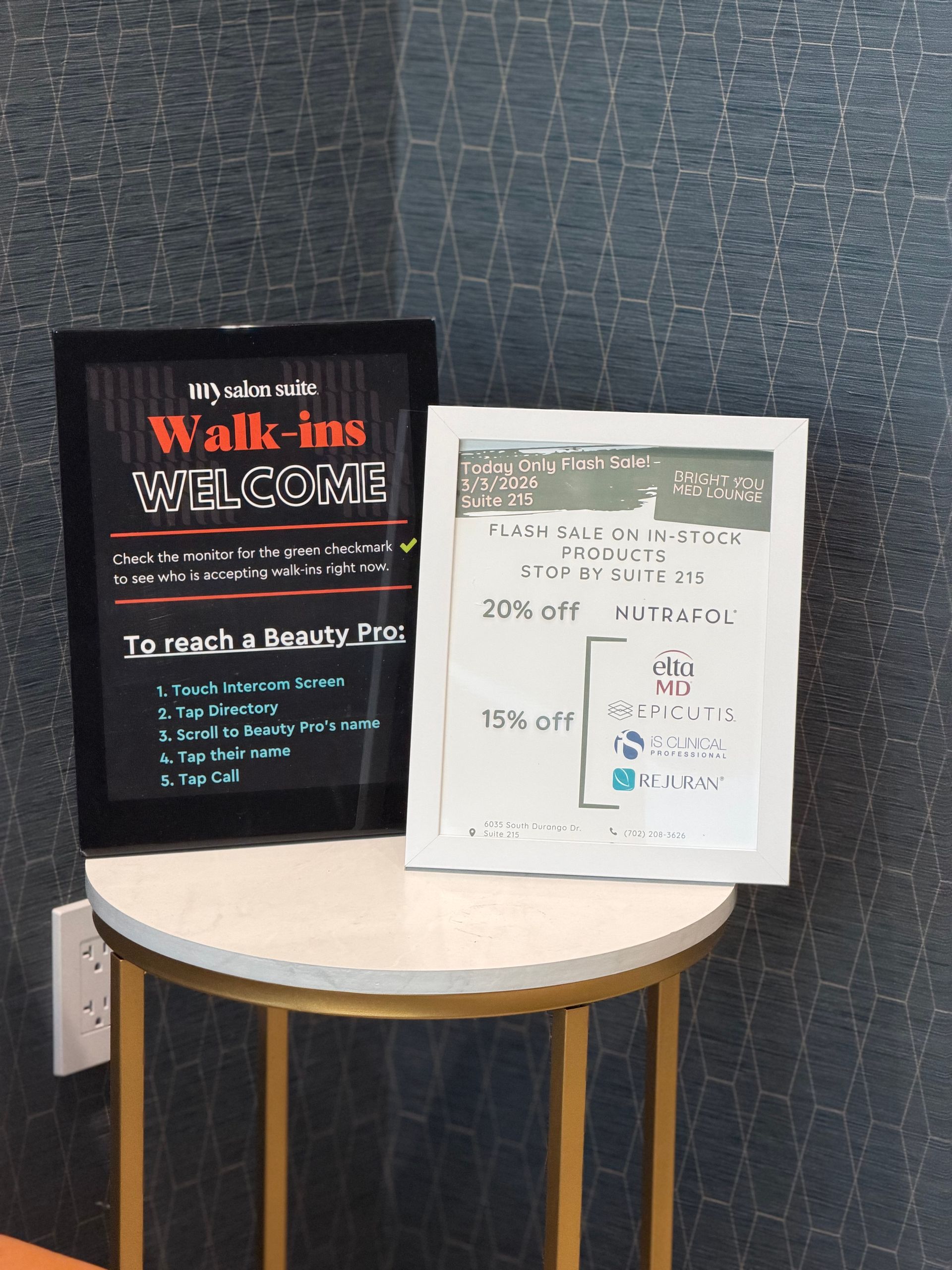 Two framed signs on a table: one says "Walk-ins Welcome," the other lists discounts.