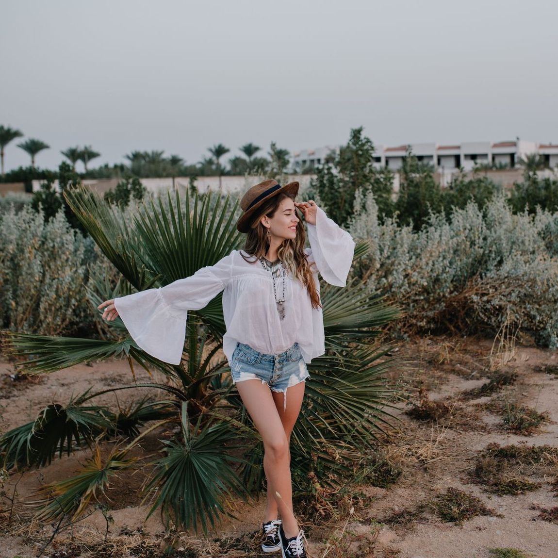 A woman in a white shirt and shorts is standing in a field.