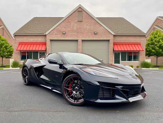 Black Corvette sports car parked in front of a brick building with red awnings.