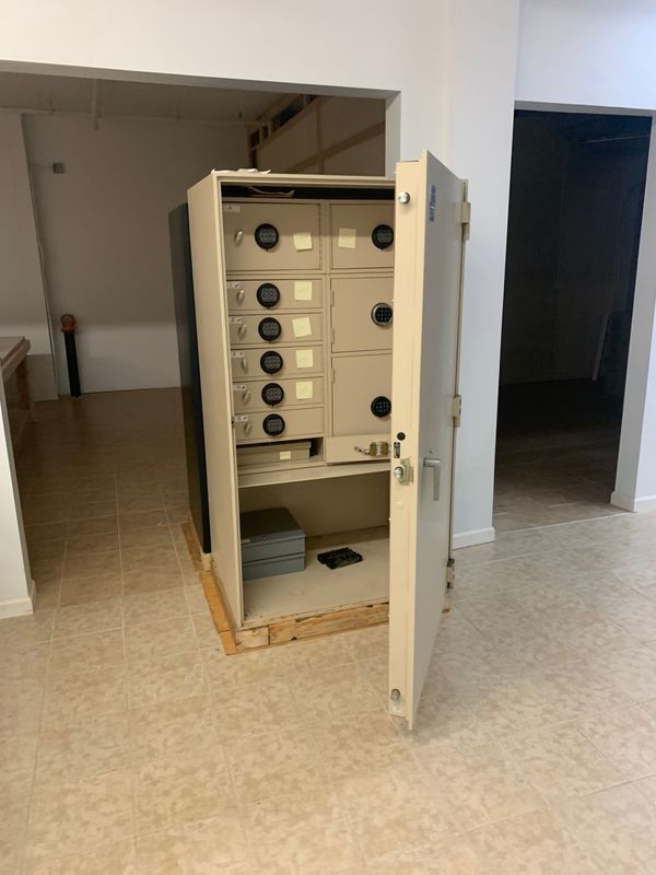 A safe with the door open is sitting on the floor in a room.