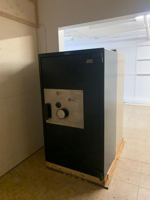 A large black safe is sitting in a room next to a door.