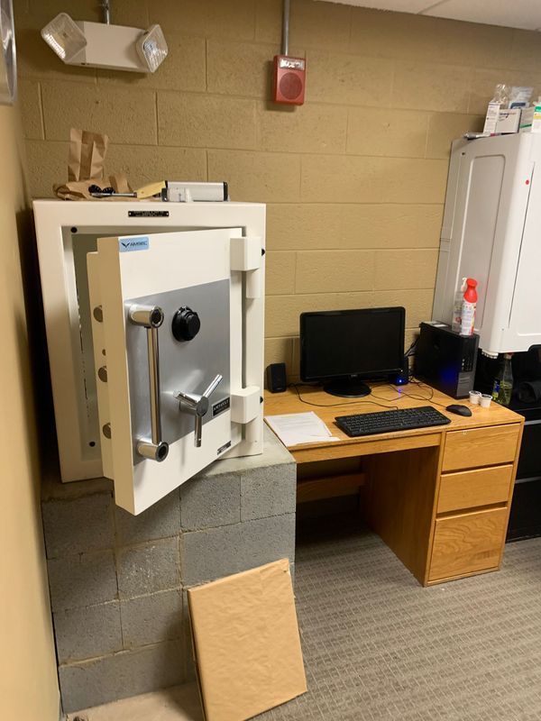 A safe is open in a room with a desk and computer