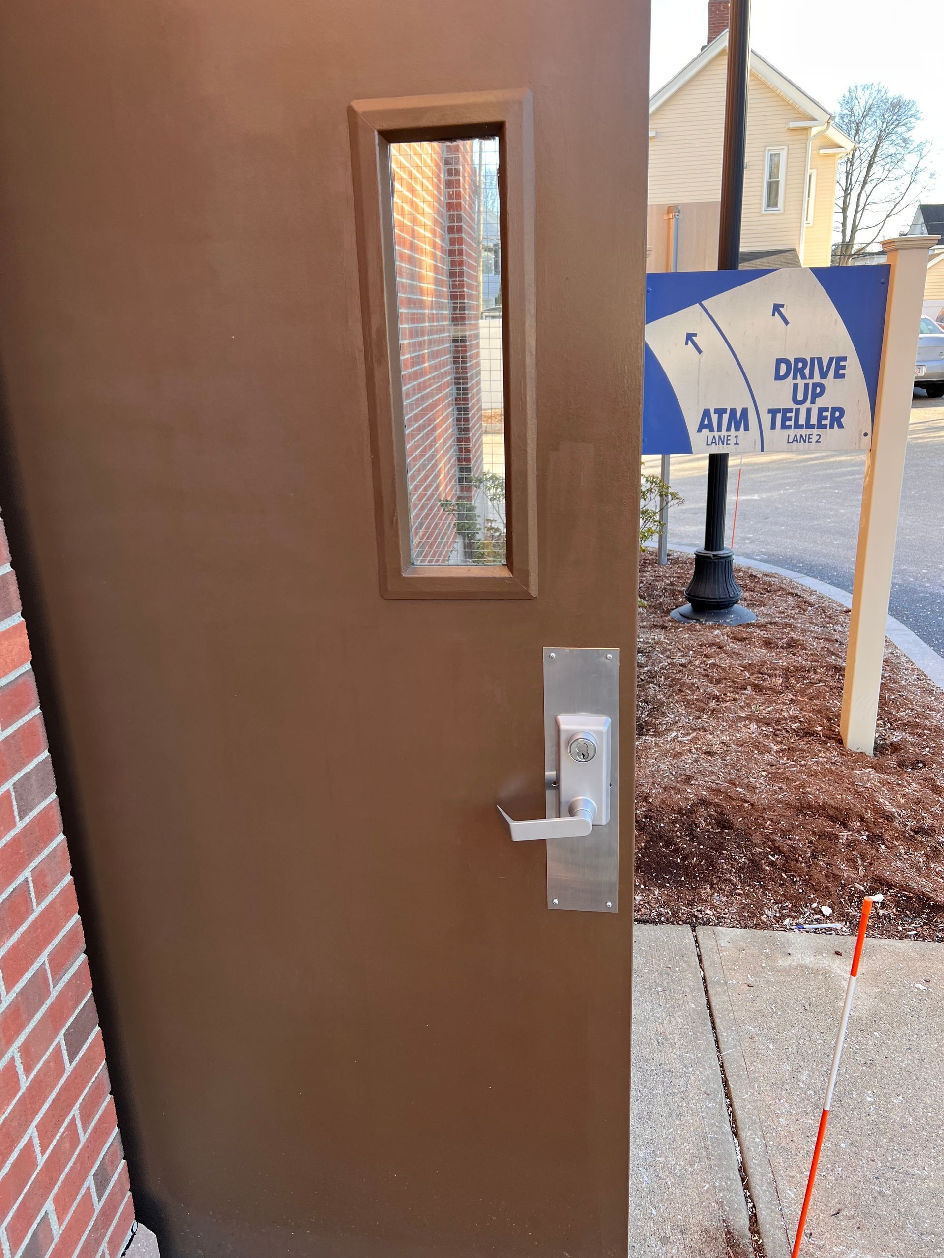 A brown door next to a sign that says drive up atm teller