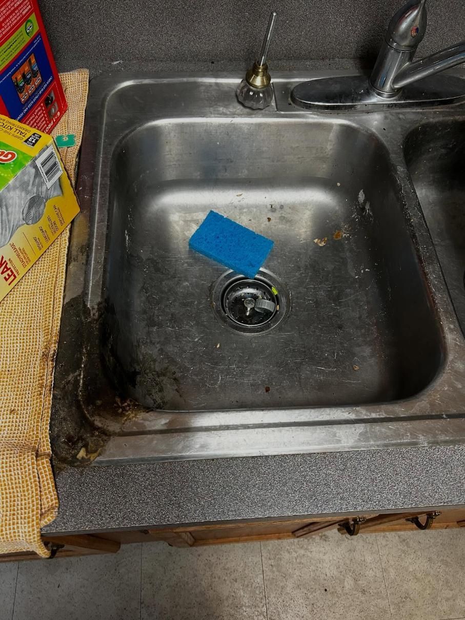 Dirty, stainless steel kitchen sink with blue sponge.