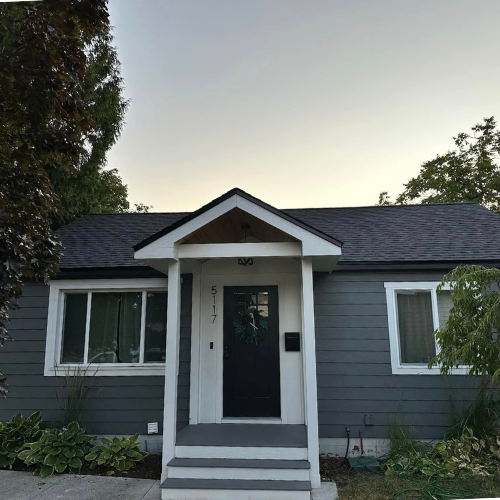 A small gray house with a porch and stairs