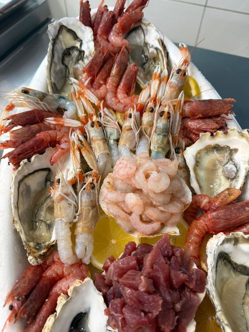 Piatto di spaghetti con pangrattato, pesce e basilico su un piatto blu. Tavola apparecchiata con posate e tovagliolo a quadretti.